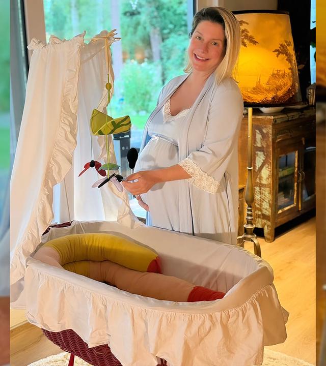 Die schwangeren Jeanette Biedermann steht vor eine Babybett.