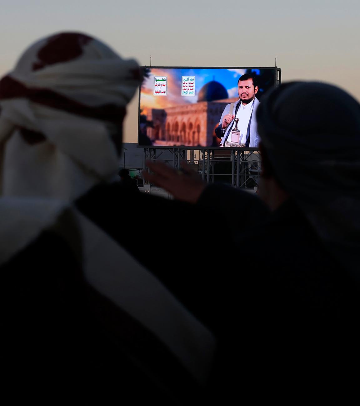 Menschen in Sana im Jemen hören eine Ansprache über eine Leinwand.