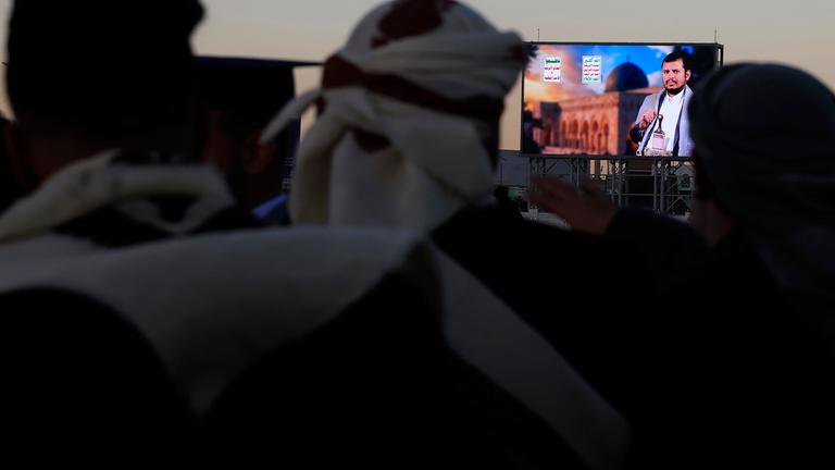 Menschen in Sana im Jemen hören eine Ansprache über eine Leinwand.