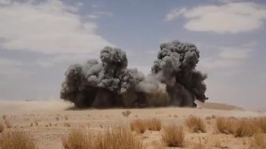 Explosion in einer Wüstengegend mit dunklem Rauch.