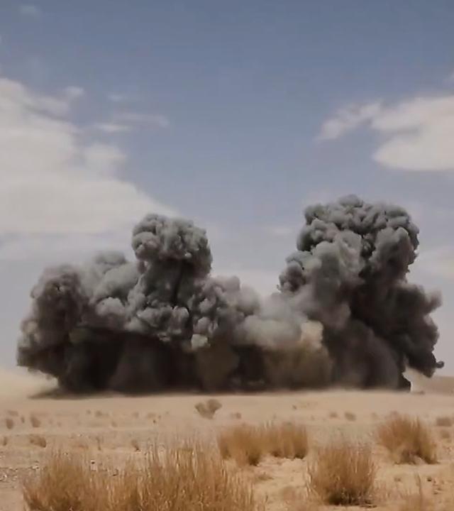 Explosion in einer Wüstengegend mit dunklem Rauch.