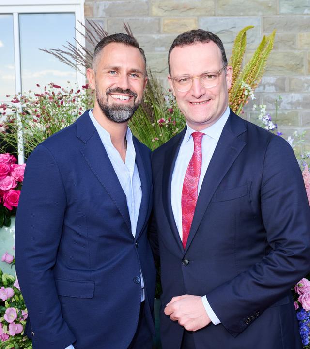 Jens Spahn und Daniel Funke stehen zusammen vor einem Blumen Arrangement