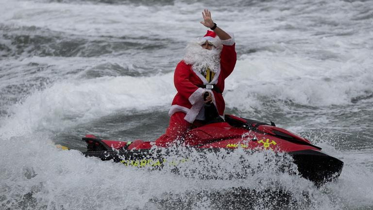Ein als Weihnachtsmann verkleideter Mann sorgt auf einem Jetski an der Copacabana für leuchtende Kinder-Augen