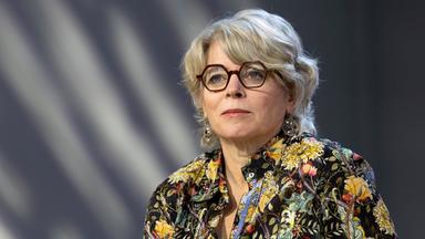 Frau mit Brille und grauen halblangen Haaren schaut an der Kamera vorbei