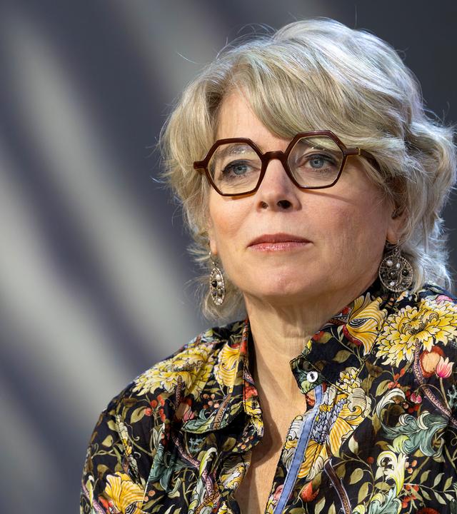 Frau mit Brille und grauen halblangen Haaren schaut an der Kamera vorbei