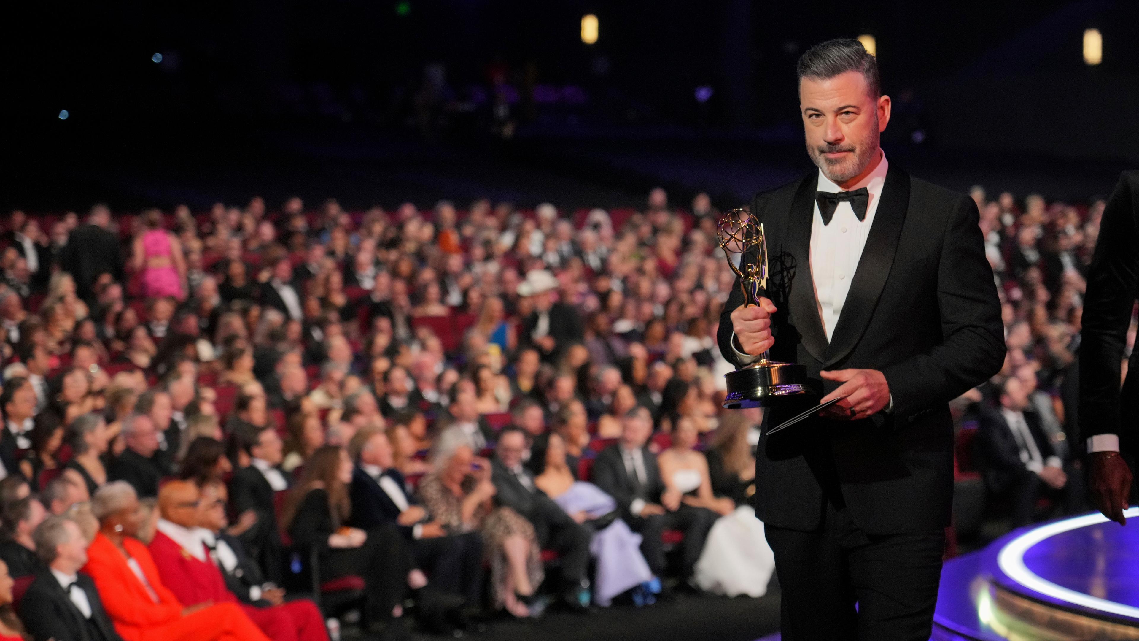 Jimmy Kimmel mit einem Emmy in der Hand. Er läuft auf die Bühne. Hinter ihm sieht man das Publikum