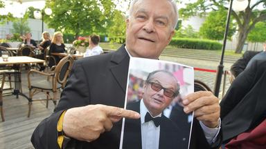 Ein Mann zeigt auf ein ausgedrucktes Foto. 
