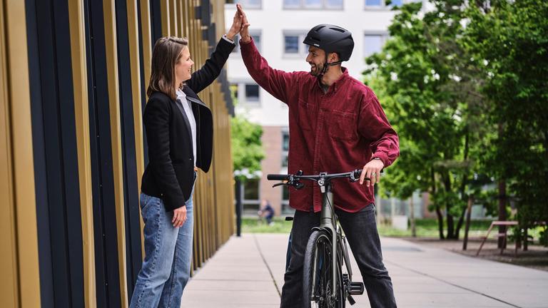 Ein Fahrradfahrer gibt seiner Arbeitgeberin die Hand.