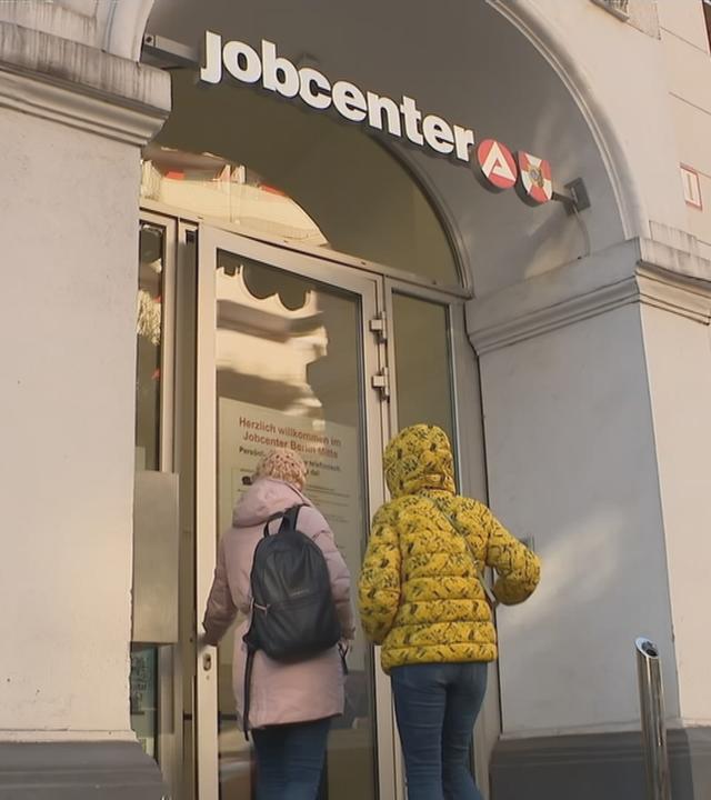 Das Bild zeigt zwei Personen, die zum Jobcenter gehen.