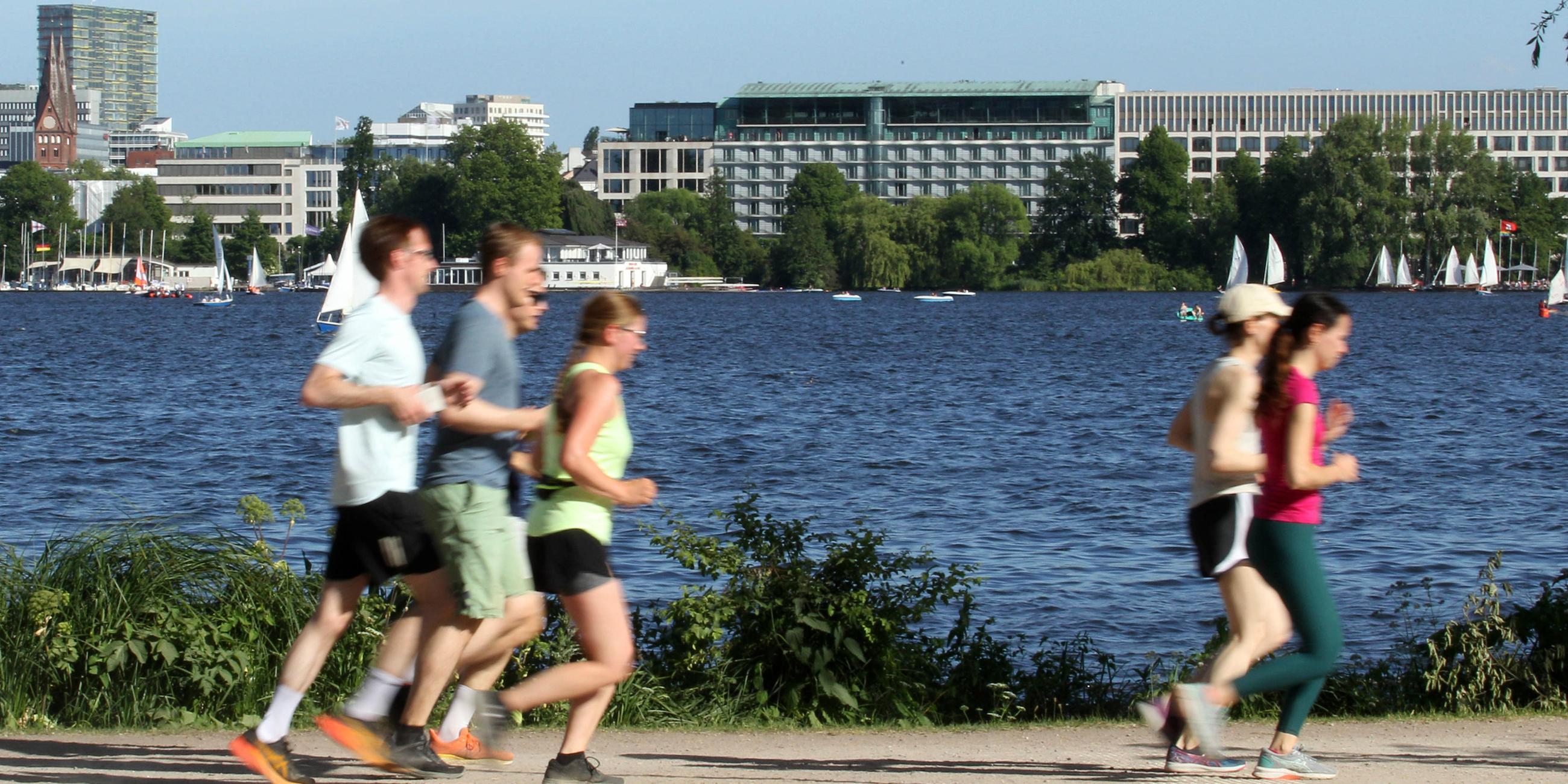 Eine Gruppe von Joggern und Joggerinnen läuft bei sommerlichen Temperaturen an der Außenalster in Hamburg entlang (Archivfroto)