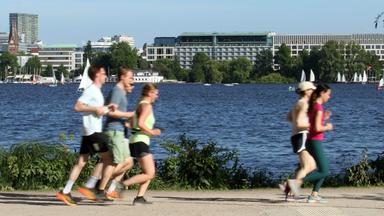 Eine Gruppe von Joggern und Joggerinnen läuft bei sommerlichen Temperaturen an der Außenalster in Hamburg entlang (Archivfroto)