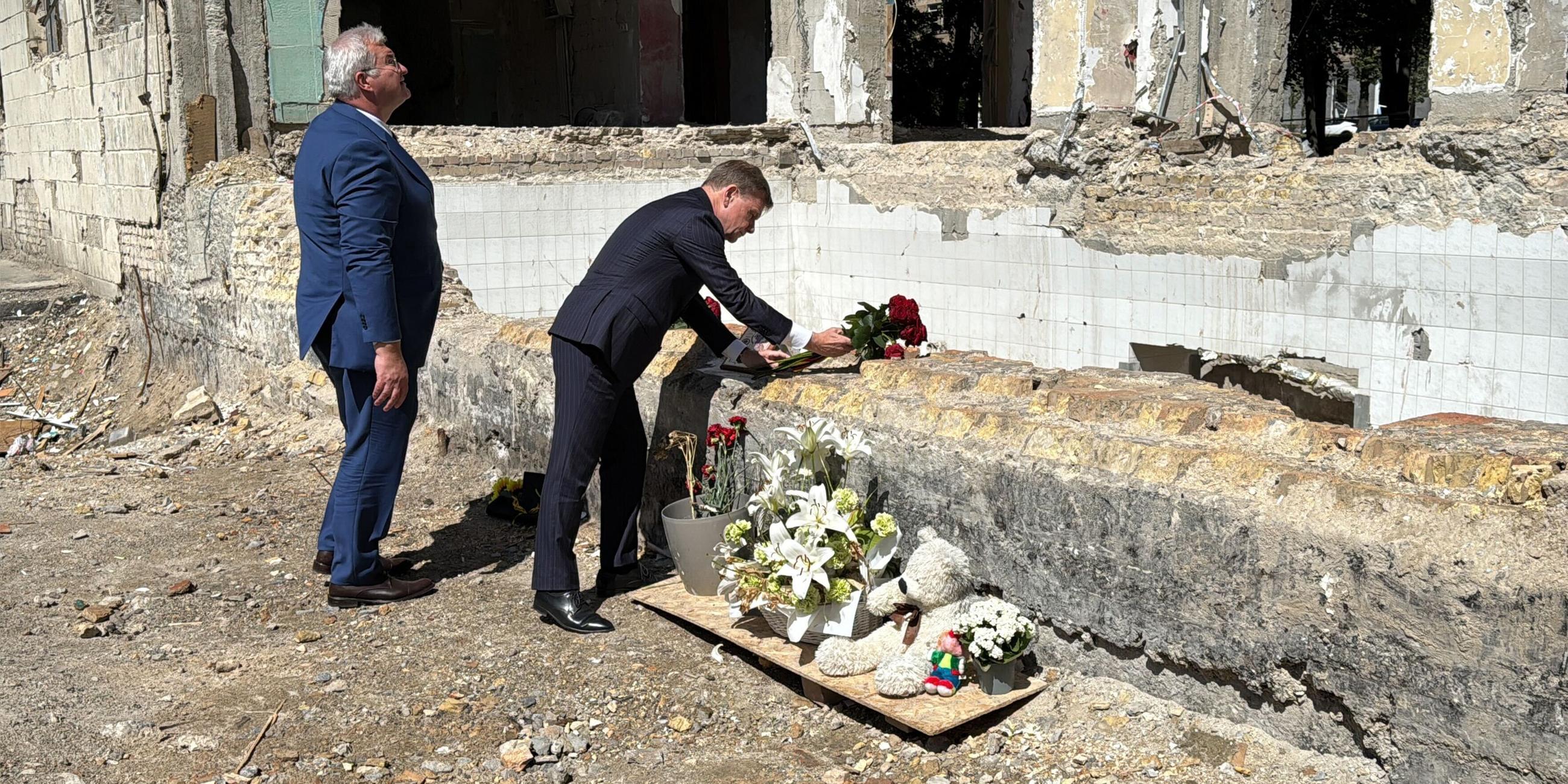 30.06.2025, Ukraine, Kiew: Johann Wadephul (r), Außenminister von Deutschland, und sein ukrainischer Amtskollege Andrij Sybiha legen Rosen nieder an einem Haus, das bei einem Raketenangriff am 17. Juni zerstört wurde.