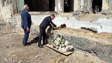 30.06.2025, Ukraine, Kiew: Johann Wadephul (r), Außenminister von Deutschland, und sein ukrainischer Amtskollege Andrij Sybiha legen Rosen nieder an einem Haus, das bei einem Raketenangriff am 17. Juni zerstört wurde.