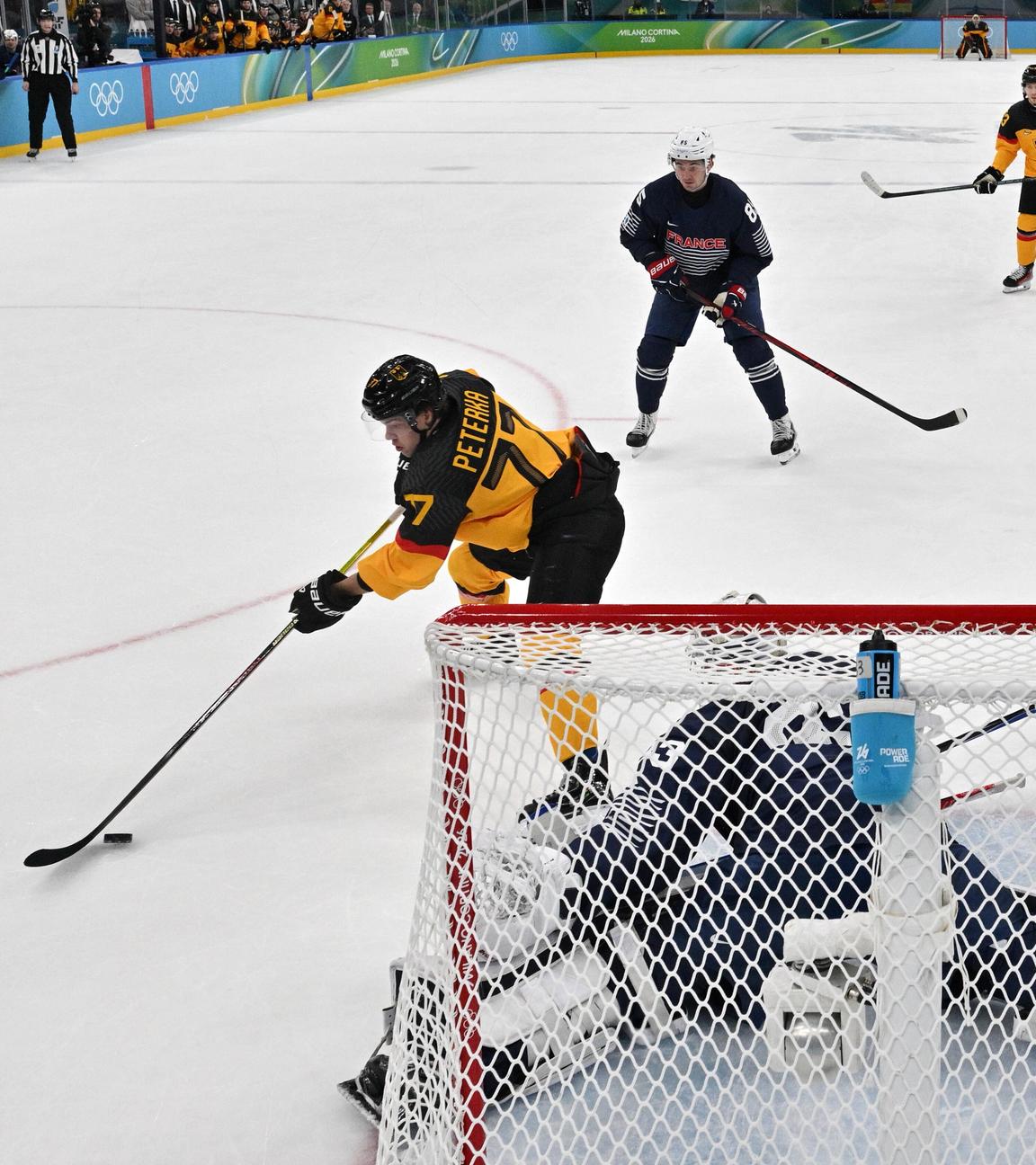 Der deutsche Eishockeyspieler John Peterka schießt bei den Olympischen Winterspielen 2026 in Cortina den Puck auf das Tor der französischen Nationalmannschaft
