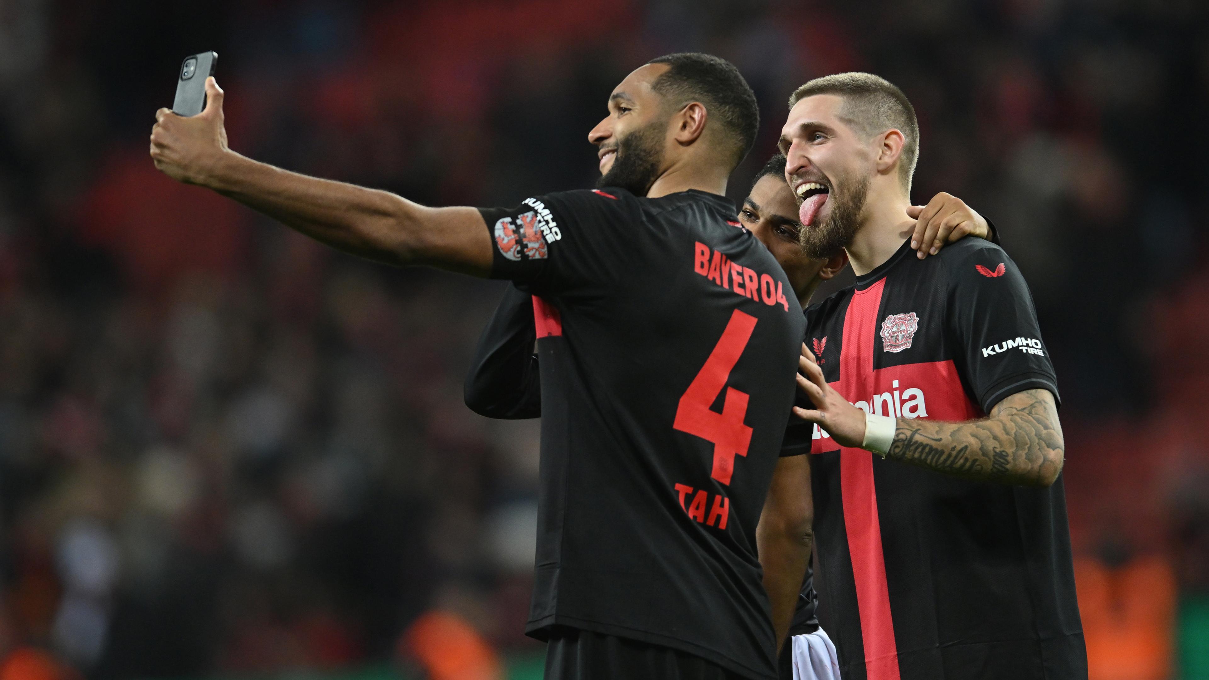 Leverkusens Jonathan Tah, Amine Adli und Robert Andrich (l-r) machen nach dem Spiel ein Selfie. 