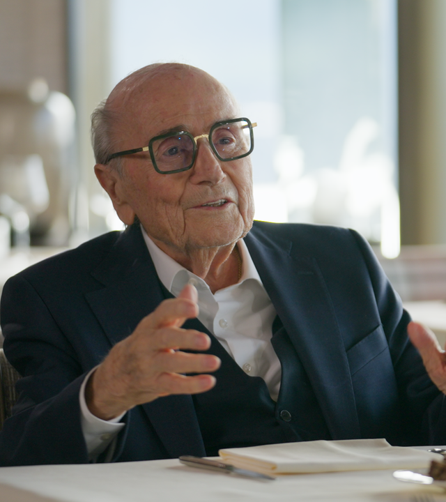 Joseph Blatter sitzt sprechend an einem weiß gedeckten Tisch.
