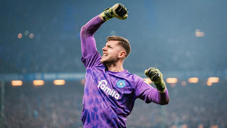 Timon Weiner hebt nach dem Sieg im Elfmeterschießen gegen den HSV vor der Gästekurve jubelnd seinen Arm 