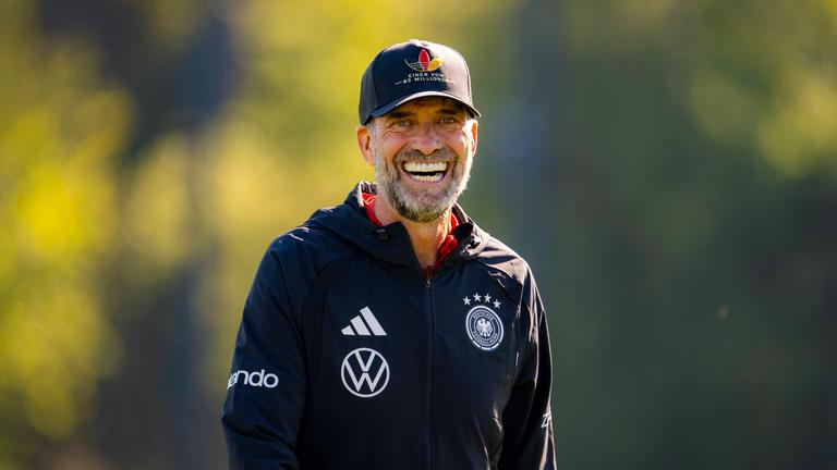 Deutscher Nationaltrainer steht lachend auf dem Platz