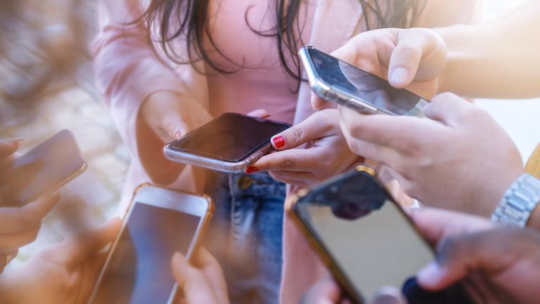 Mehrere Menschen stehen zusammen mit ihren Smartphones.