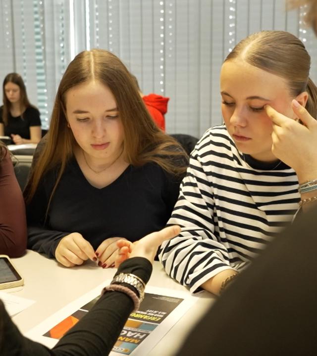 Drei Jugendliche sitzen im Klassenzimmer und reden miteinander vor der Landtagswahl 2026 in Baden-Württemberg.