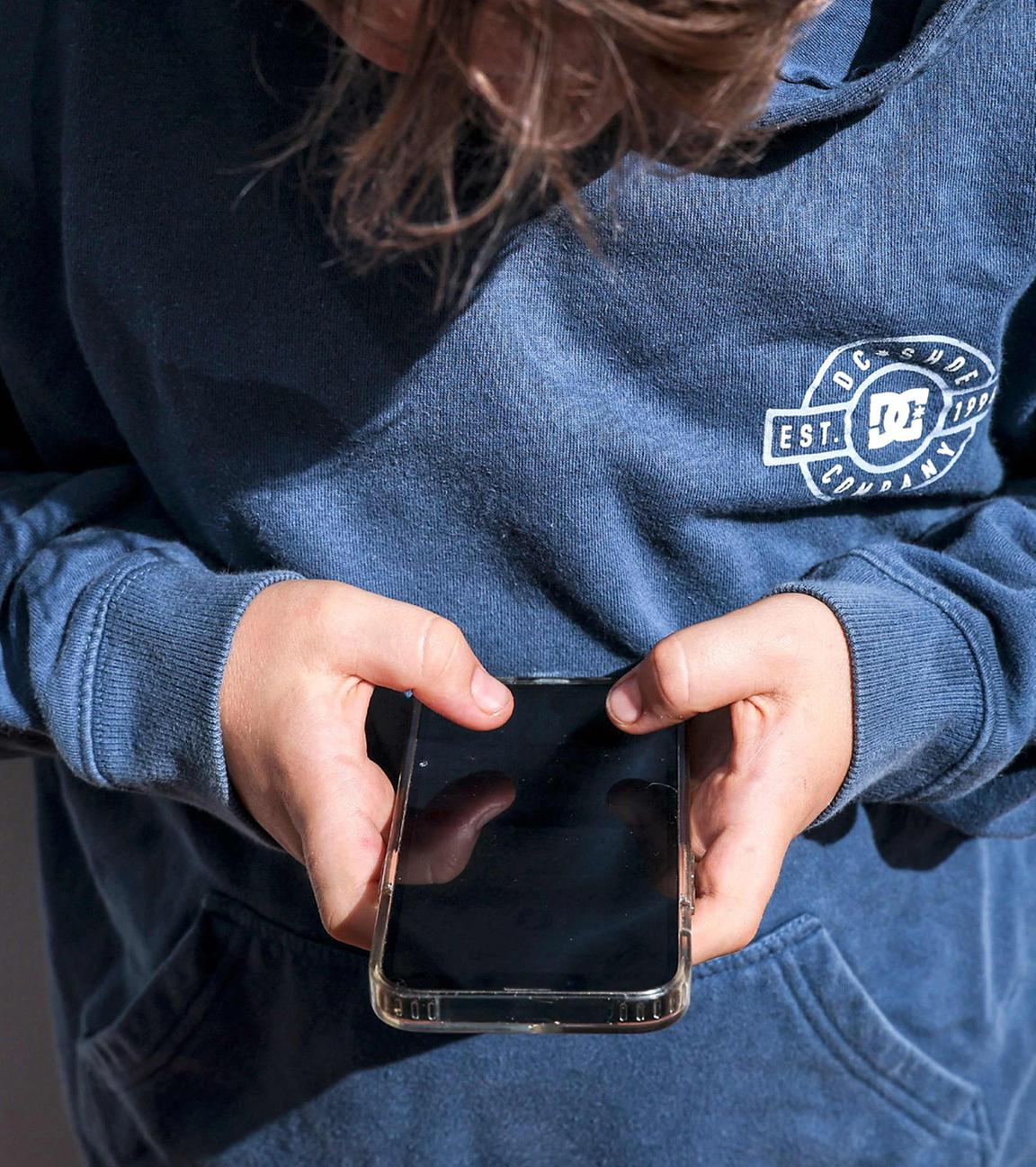 Ein Jugendlicher schaut auf sein Handy. (Symbolfoto)