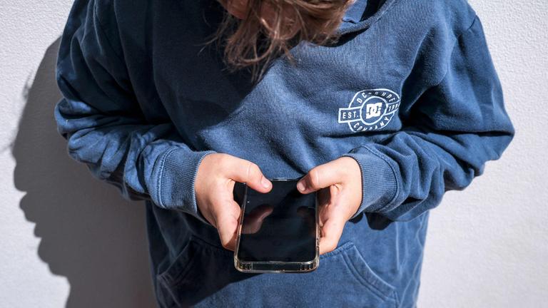 Ein Jugendlicher schaut auf sein Handy. (Symbolfoto)