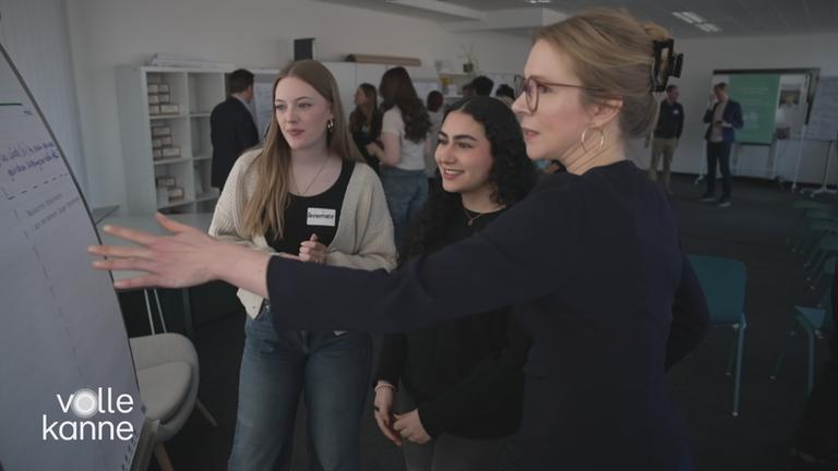 Eine ältere und zwei jüngere Frauen vor einem Whiteboard