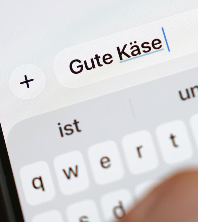 Die Wörter Gute Käse sind auf dem Display eines Smartphones zu lesen.