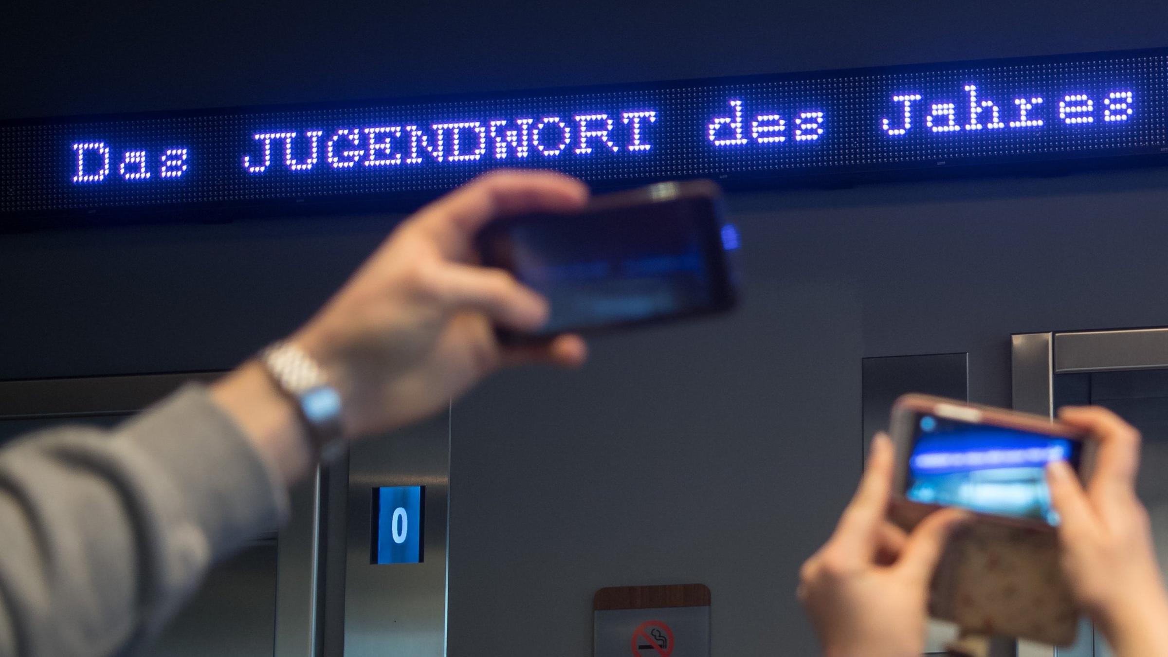 Bayern, München: Auf einem Laufband erscheint "Jugendwort des Jahres" über den digitalen Newsticker eines Hotels in München. Archivbild