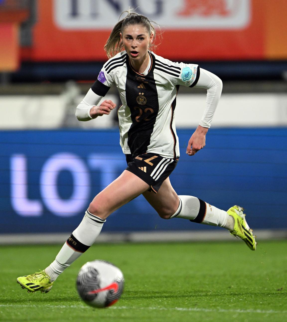 Jule Brand rennt auf einem Fußballfeld einem Ball hinterher