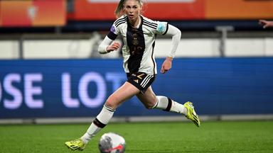 Jule Brand rennt auf einem Fußballfeld einem Ball hinterher