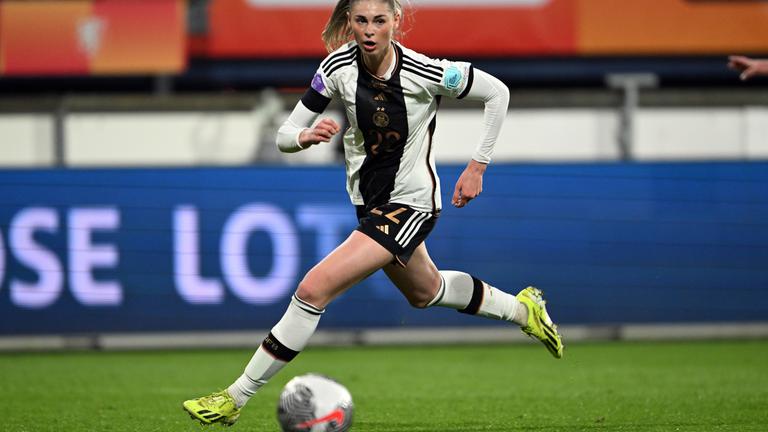 Jule Brand rennt auf einem Fußballfeld einem Ball hinterher