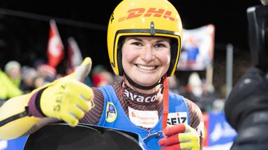 Julia Taubitz hält einen Daumen hoch und lächelt in die Kamera
