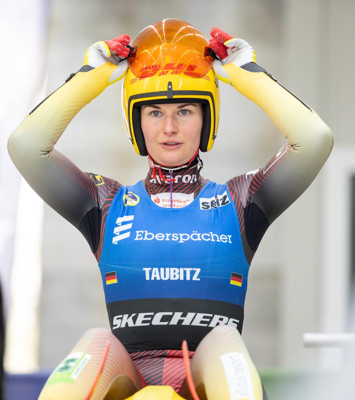 Julia Taubitz bereitet sich auf das Rodeln vor und richtet ihren Helm und den Gesichtsschutz