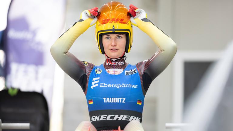 Julia Taubitz bereitet sich auf das Rodeln vor und richtet ihren Helm und den Gesichtsschutz