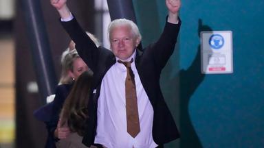 Julian Assange streckt seine Arme noch oben und zeigt zwei Daumen nach oben.