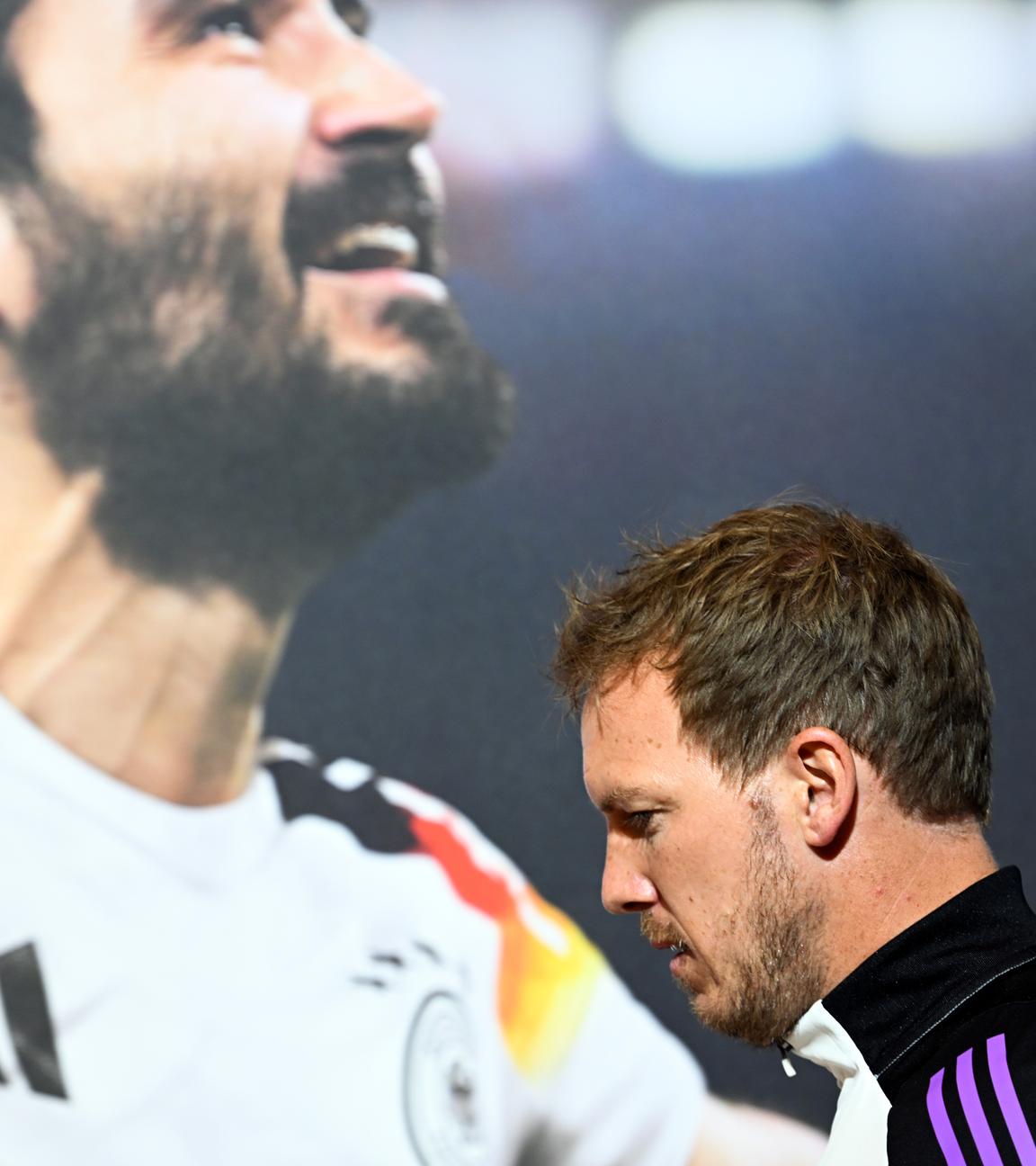 Deutschlands Trainer Julian Nagelsmann kommt an einem Bild von Ilkay Gündogan vorbei zur Pressekonferenz am 02.06.24.