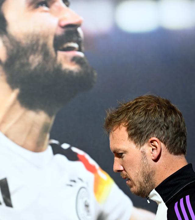 Deutschlands Trainer Julian Nagelsmann kommt an einem Bild von Ilkay Gündogan vorbei zur Pressekonferenz am 02.06.24.