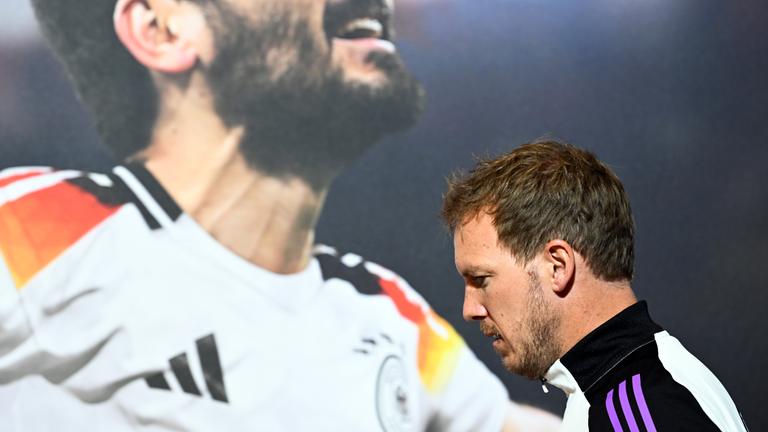 Deutschlands Trainer Julian Nagelsmann kommt an einem Bild von Ilkay Gündogan vorbei zur Pressekonferenz am 02.06.24.