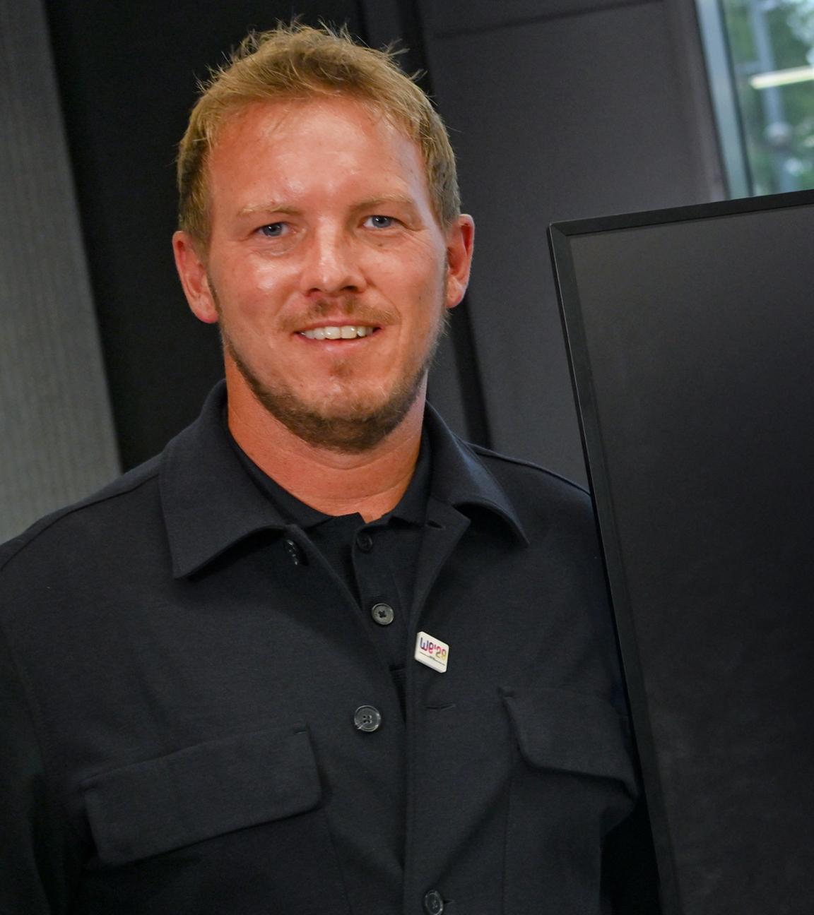 Bundestrainer Julian Nagelsmann steht im Anschluss an die Pressekonferenz des Deutschen Fußball-Bundes (DFB) neben einem Monitor, auf dem der Kader für den Start in die Qualifikationsrunde zur WM 2026 zu sehen ist. 