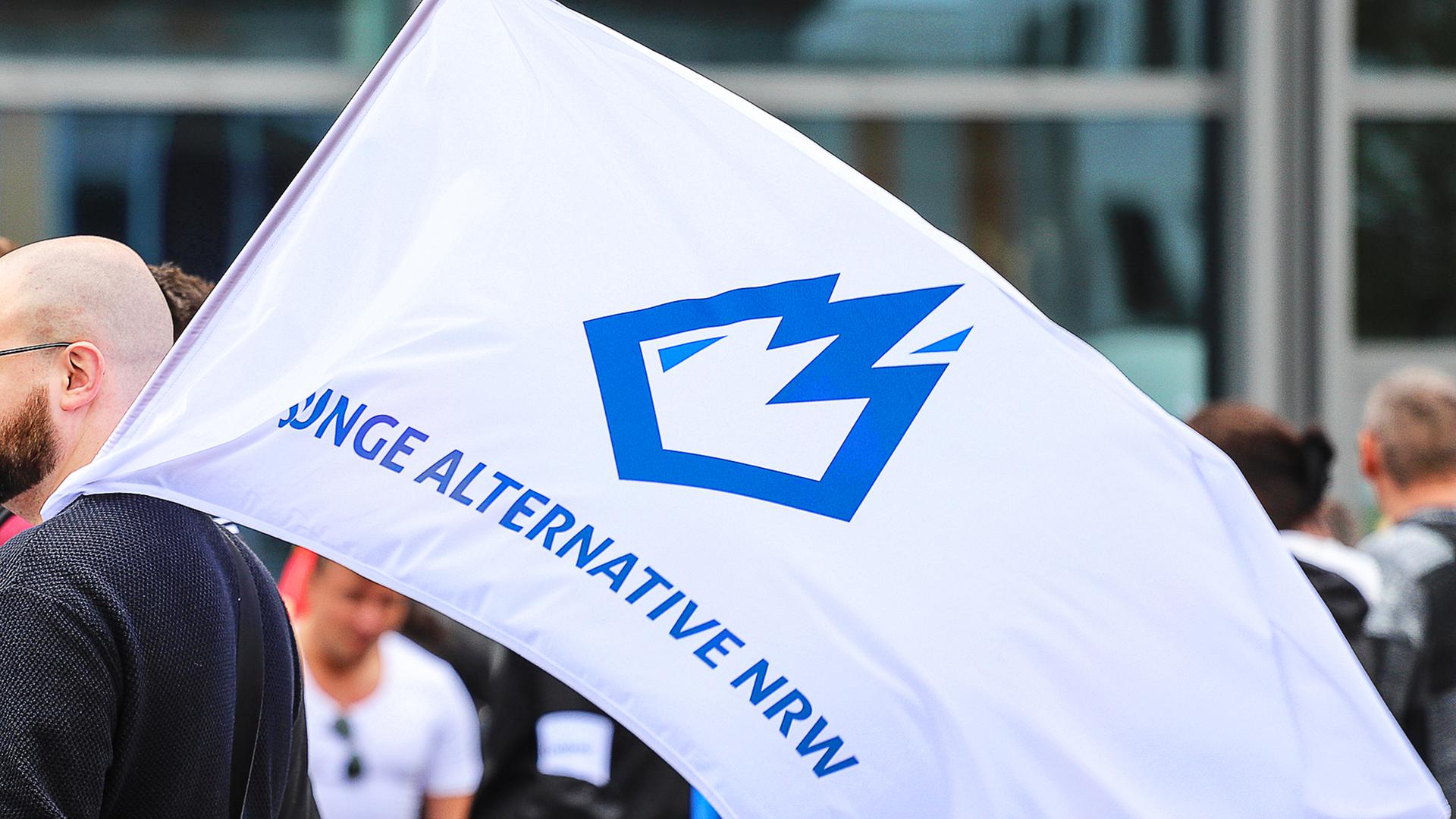 Ein Mitglied der "Jungen Alternative", Jugendorganisation der AfD, trägt auf einer Wahlkampfveranstaltung eine Fahne mit dem Logo der Organisation.