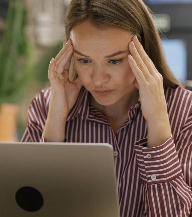 Ein junge Frau sitzt müde im Büro
