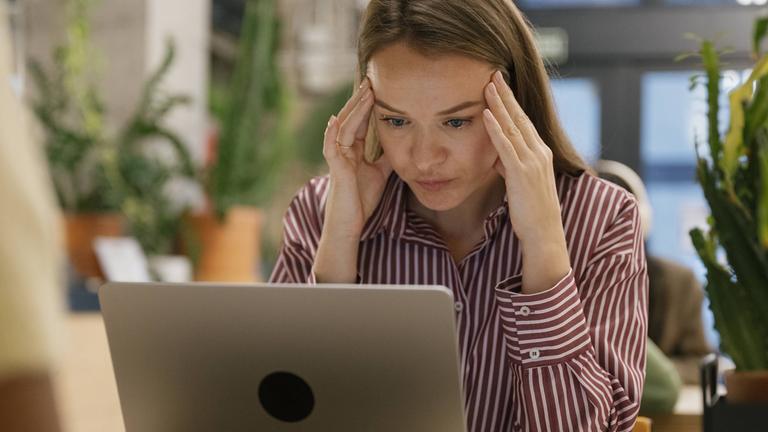 Ein junge Frau sitzt müde im Büro