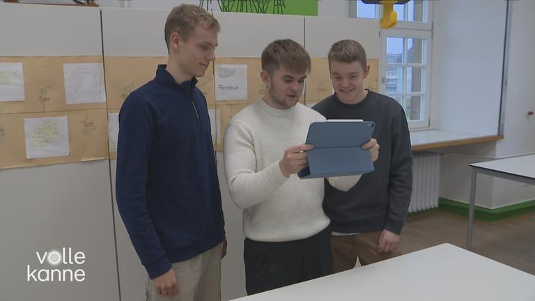 Drei junge Männer schauen auf ein iPad