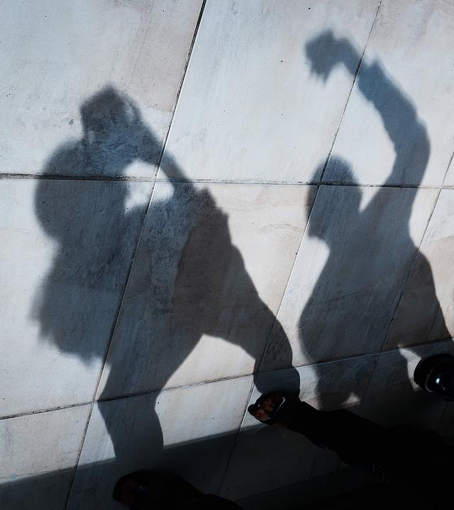 Der Schatten von jungen Menschen mit Smartphones und Tablets ist an einer Wand zu sehen.