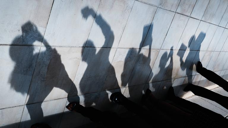 Der Schatten von jungen Menschen mit Smartphones und Tablets ist an einer Wand zu sehen.