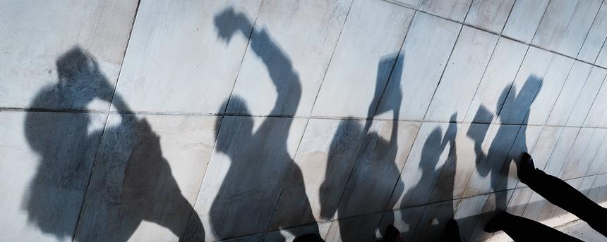 Der Schatten von jungen Menschen mit Smartphones und Tablets ist an einer Wand zu sehen.
