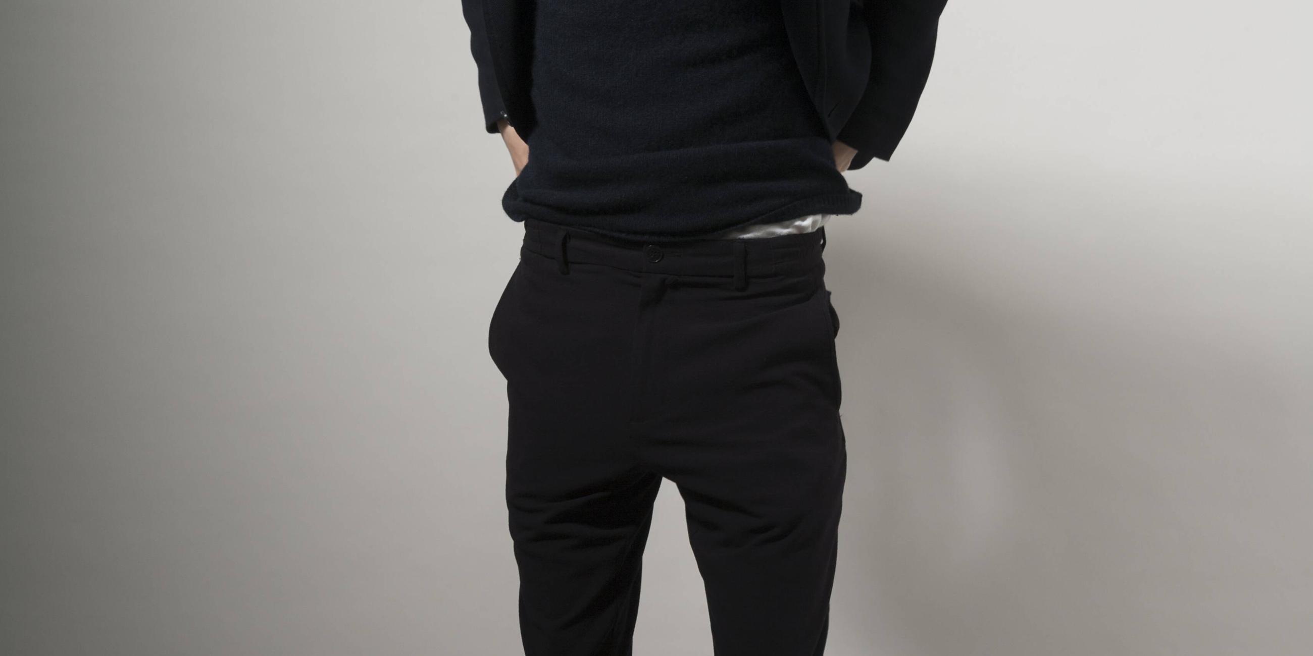 Ein junger schlanker Mann zieht sich die Hose am Bund hoch.