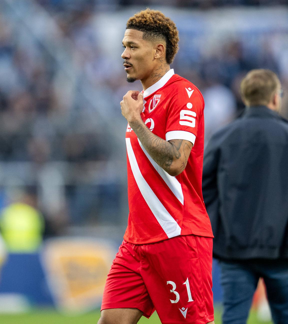 Justin Butler geht alleine mit bedrücktem Blick über das Spielfeld