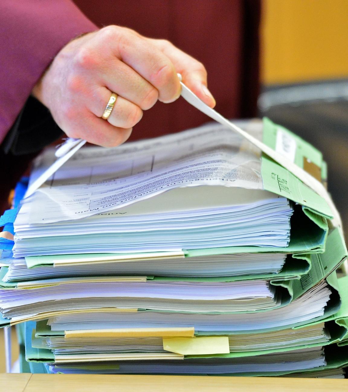 "Justiz am Limit - Der Kampf gegen Wirtschaftskriminelle": Eine Hand hält einen Aktenstapel im Gerichtssaal des Bundesarbeitsgerichts.